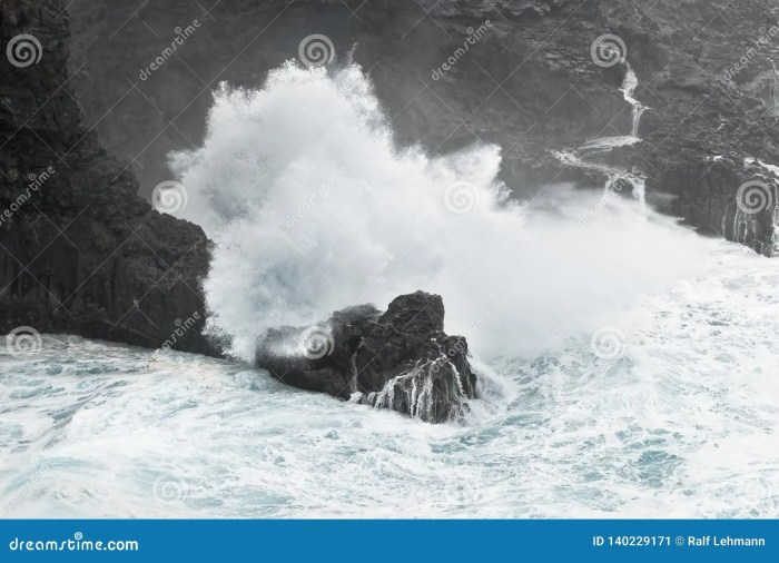Stormy sea on sunset. The waves crash into the volcanic basalt rock ...